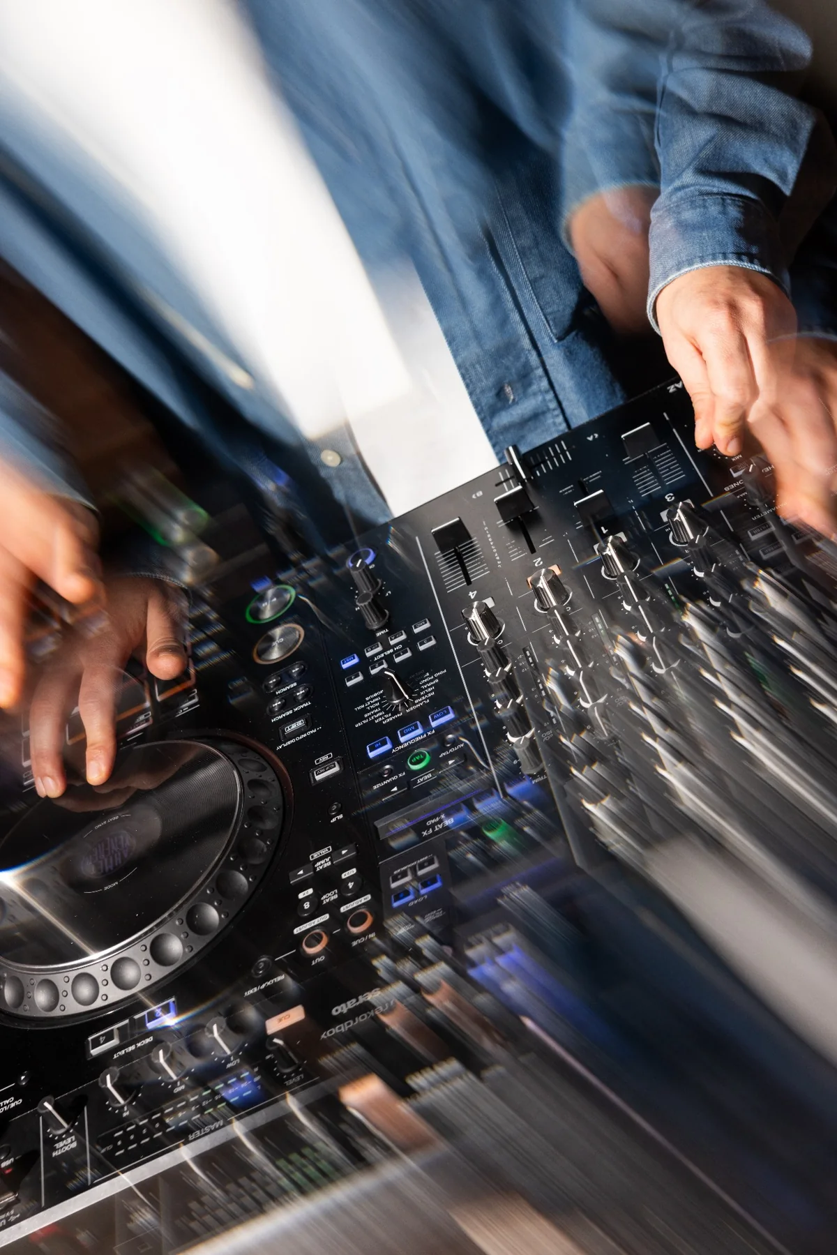 Hands moving across the DJ mixer