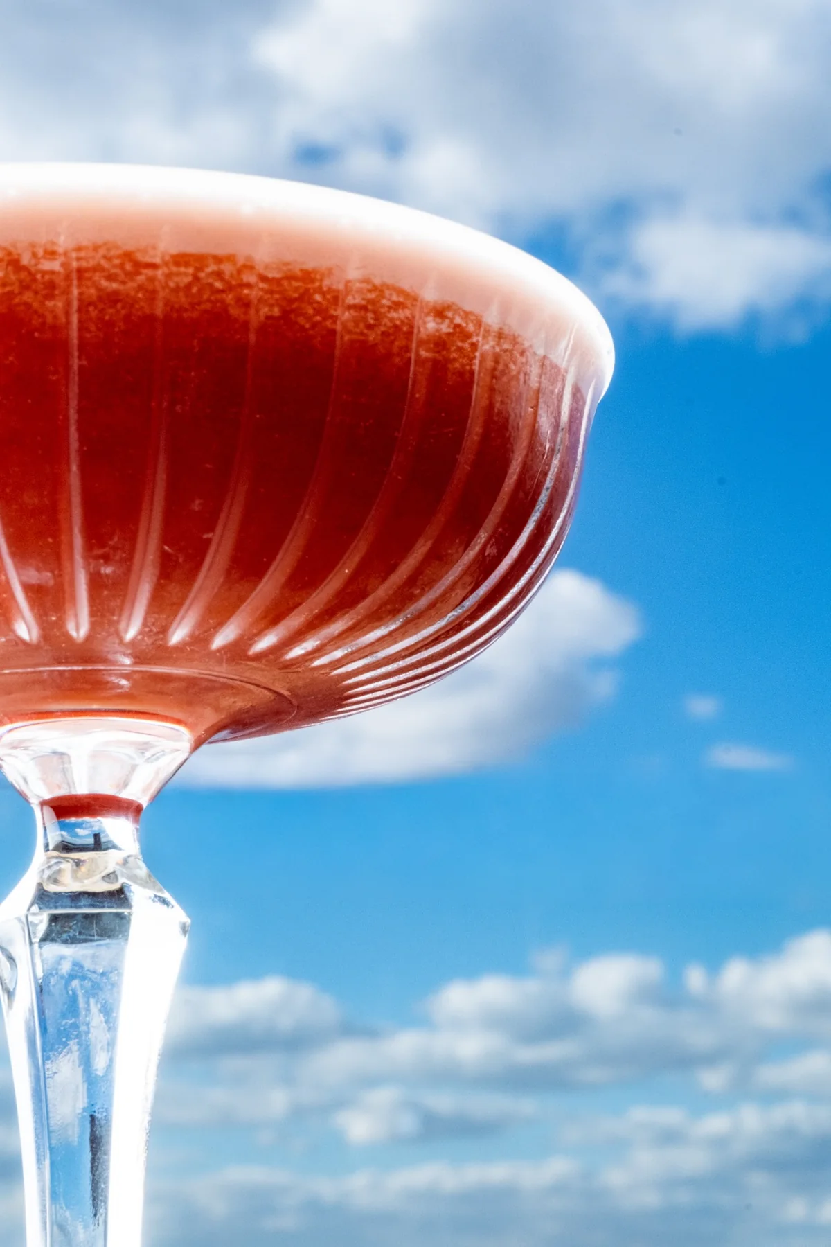 Close detail of a pink cocktail against the sky